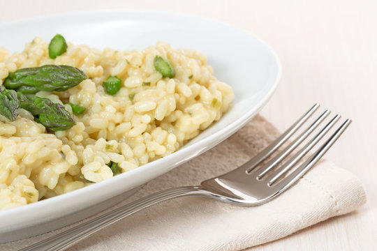 risotto dish with asparagus and fork on beige napkin