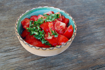 fresh tomato salad with basil in ceramic bowl on rustic wooden table