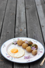 Fried egg with cooked potatoes on a white plate.