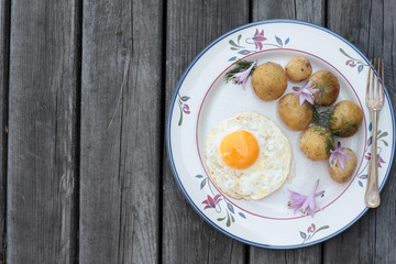 Fried egg with cooked potatoes on a white plate.