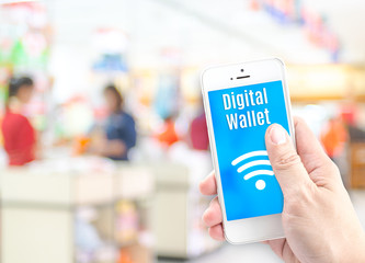 Hand holding mobile phone with digital wallet at supermarket blu