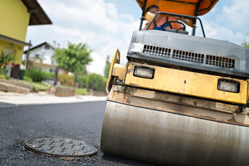 Compactor roller at asphalting work.
Road roller flattening new asphalt.