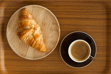 Crispy fresh croissants and cup of coffee espresso on wood backg