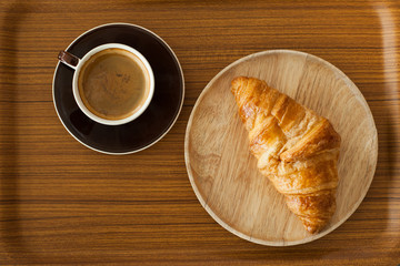 Crispy fresh croissants and cup of coffee espresso on wood backg