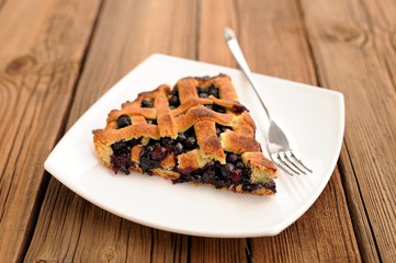 Piece of delicious homemade lattice pie with whole wild blueberr