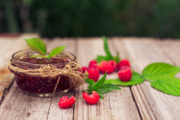 raspberry jam in a jar and fresh berries on the wooden table