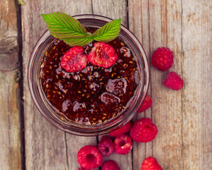 raspberry jam in a jar and fresh berries on the wooden table