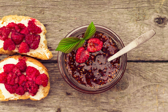 raspberry jam in a jar and fresh berries on the wooden table