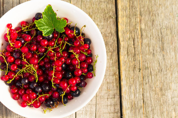 Fresh ripe currant berries bowl on wooden table background