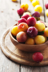 Yellow and red sweet plums on the wooden table