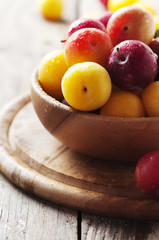Yellow and red sweet plums on the wooden table