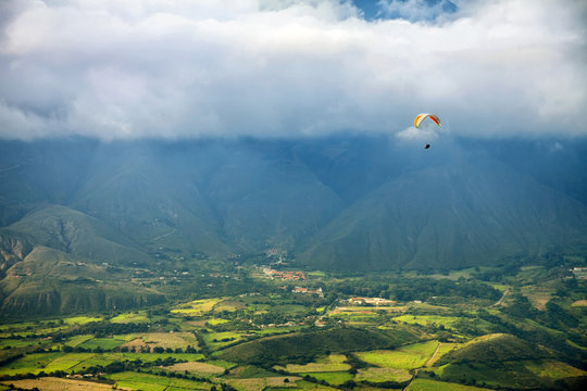 Paragliding in mountains above fields and villages - view from air 