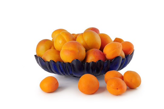 Ripe apricots in a blue plate on a white background