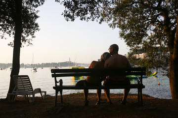 Couple sitting on bench at sunset