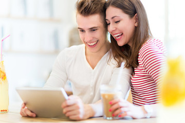 Couple using digital tablet at cafe
