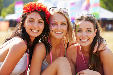 Three girl friends at a music festival looking to camera