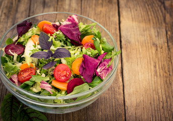 Fresh mixed salad in the bowl on the wooden table