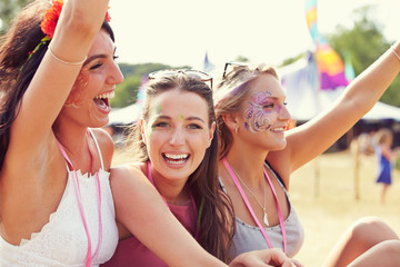Three girl friends at a music festival, one turned to camera