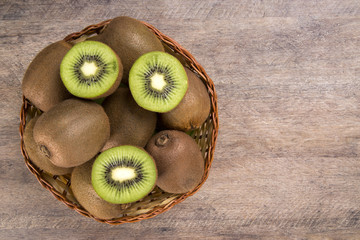 Some kiwis in a basket over a wooden surface