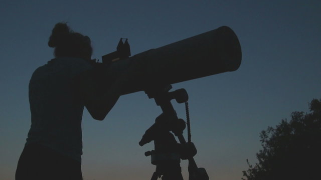 Young female watching the stars through a telescope.