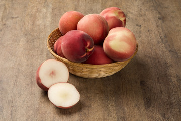 Some peaches in a basket over a wooden surface