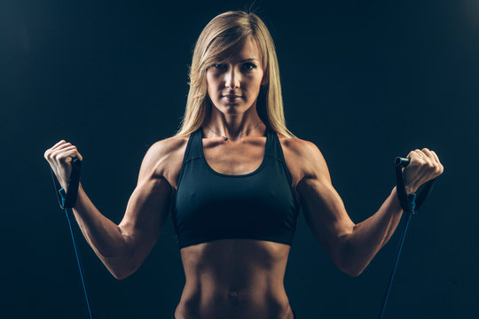 Athletic young woman working on biceps with expander