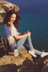 Girl backpacker is sitting on rock over sea view