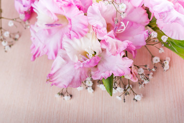 branch of pink gladiolus on wooden table. Vintage flower background. Soft focus.