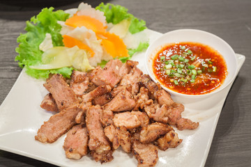 Grill pork with spicy sauce on white dish.
