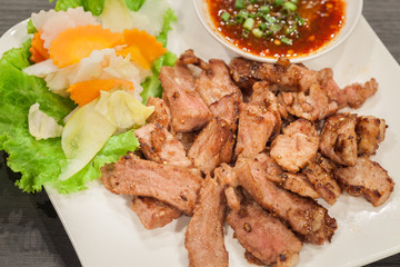 Grill pork with spicy sauce on white dish.