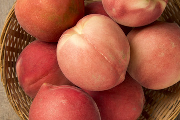 Some peaches in a basket over a wooden surface