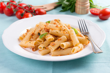 Plate of penne pasta with bread crumbs, basil and cherry