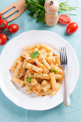 Plate of penne pasta with bread crumbs, basil and cherry