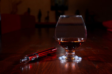 Ein Glas Cognac mit e-Zigarette