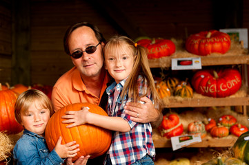 Fototapeta premium Father and two kids picking out pumpkin on the farm market