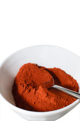 Red paprika powder in a bowl, on a white background.