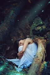 Beautiful dark woman sleeping among forest spirits