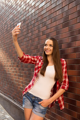 Obraz premium Girl with smartphone making selfie photo