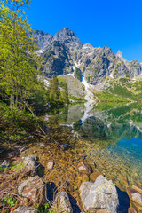 Naklejka na ściany i meble Reflection of mountain peaks in beautiful green water Morskie Oko lake, Tatra Mountains, Poland