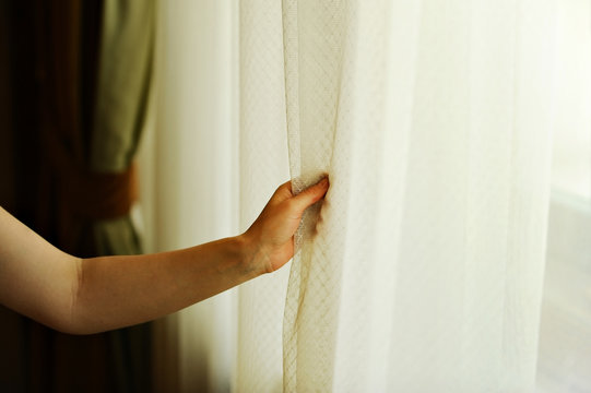 Hand Pulling A Window Curtain