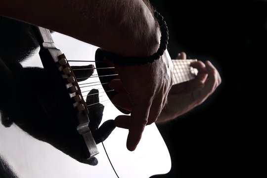 Acoustic guitar close-up with fingers playing it