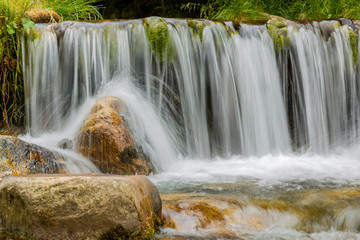 Fototapeta premium Waterfall on a mountain river with rock and forest in background