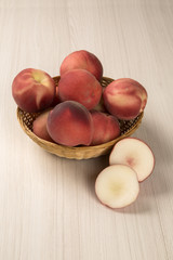 Some peaches in a basket over a white background