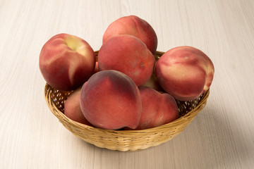 Some peaches in a basket over a white background