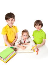 three schoolchildren are drawing in the notebook on the table