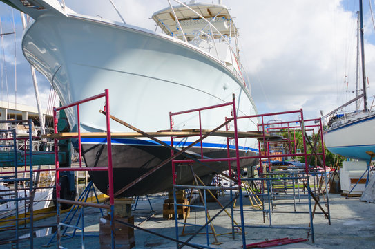 Boatyard repair big powerboat on racks surrounded with work scaffolding