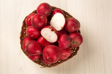 Some radishes in a basket over a white background