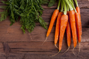 Carrots bunch with leaves shot from above on a wooden background cropped in