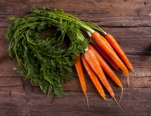 Carrots bunch with leaves shot from above on a wooden background 