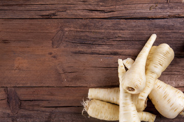 Parsnip bunch in a corner with negative space shot on a wooden background from above